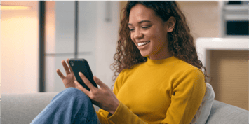woman on her couch using mobile device