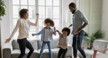 Family of four celebrating and dancing in their living room