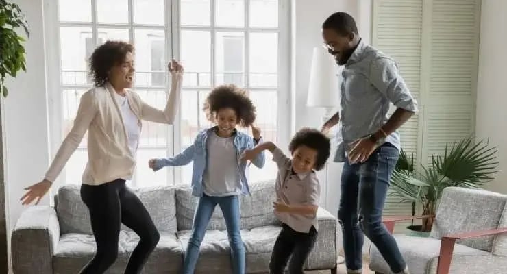  Family of four celebrating and dancing in their living room