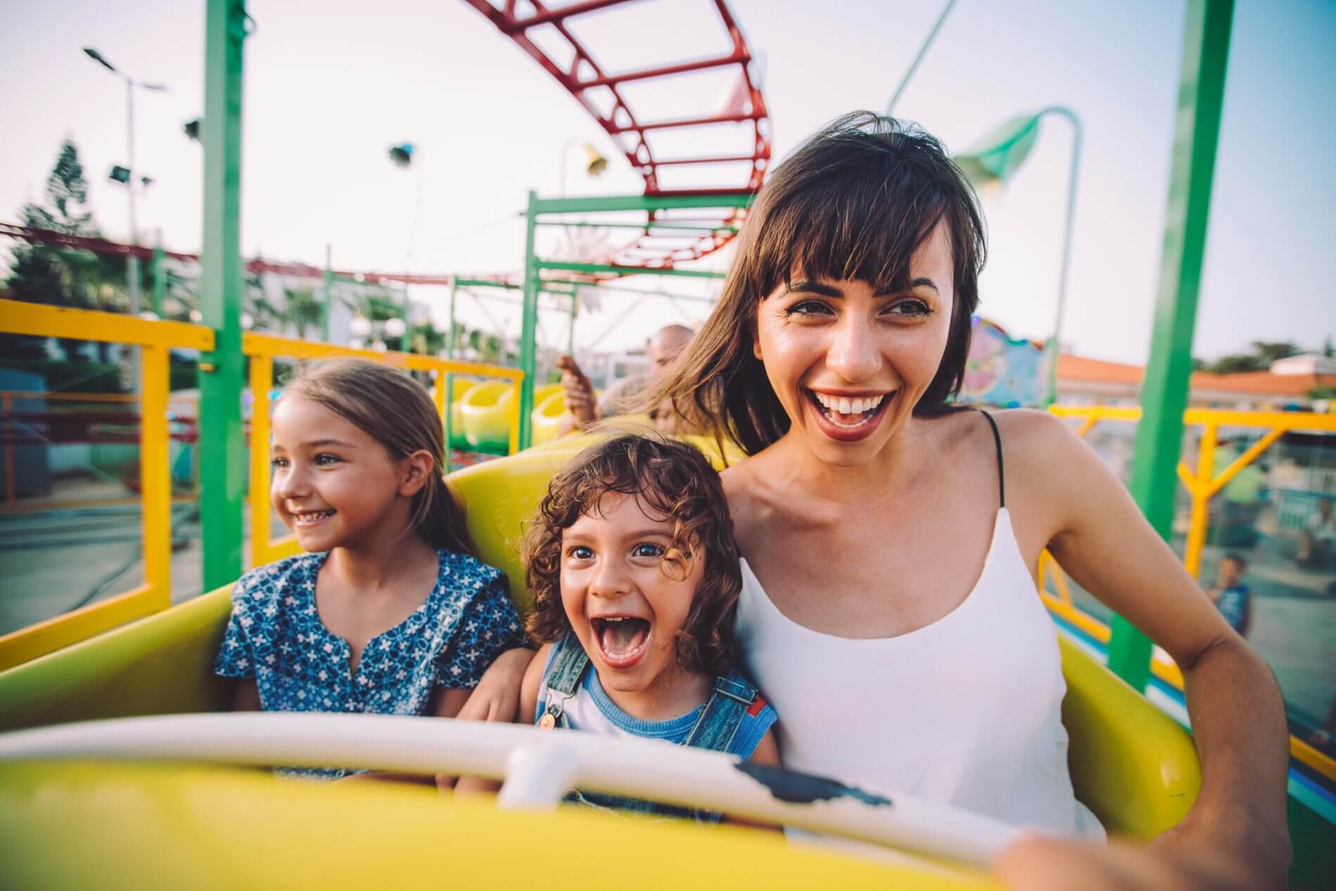 mom and daughters on a ride at the theme park