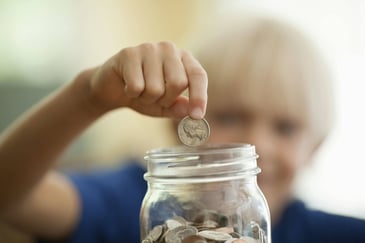 kid saving money into a jar for fundraising