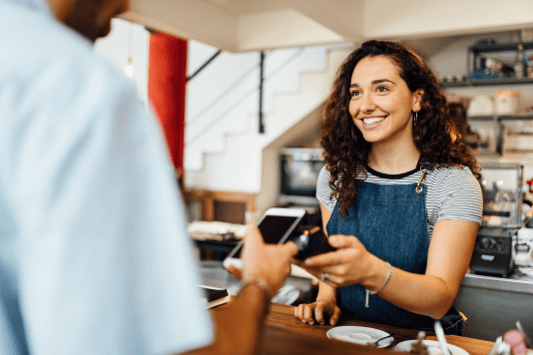 Female customer at a coffee shop paying with gift card on her phone